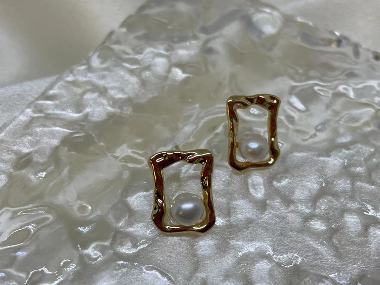 Gold quadrate stud earrings with a single freshwater pearl in each.