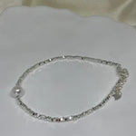 A silver beaded bracelet with a single freshwater pearl and a heart charm.