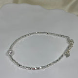 A silver beaded bracelet with a single freshwater pearl and a heart charm.