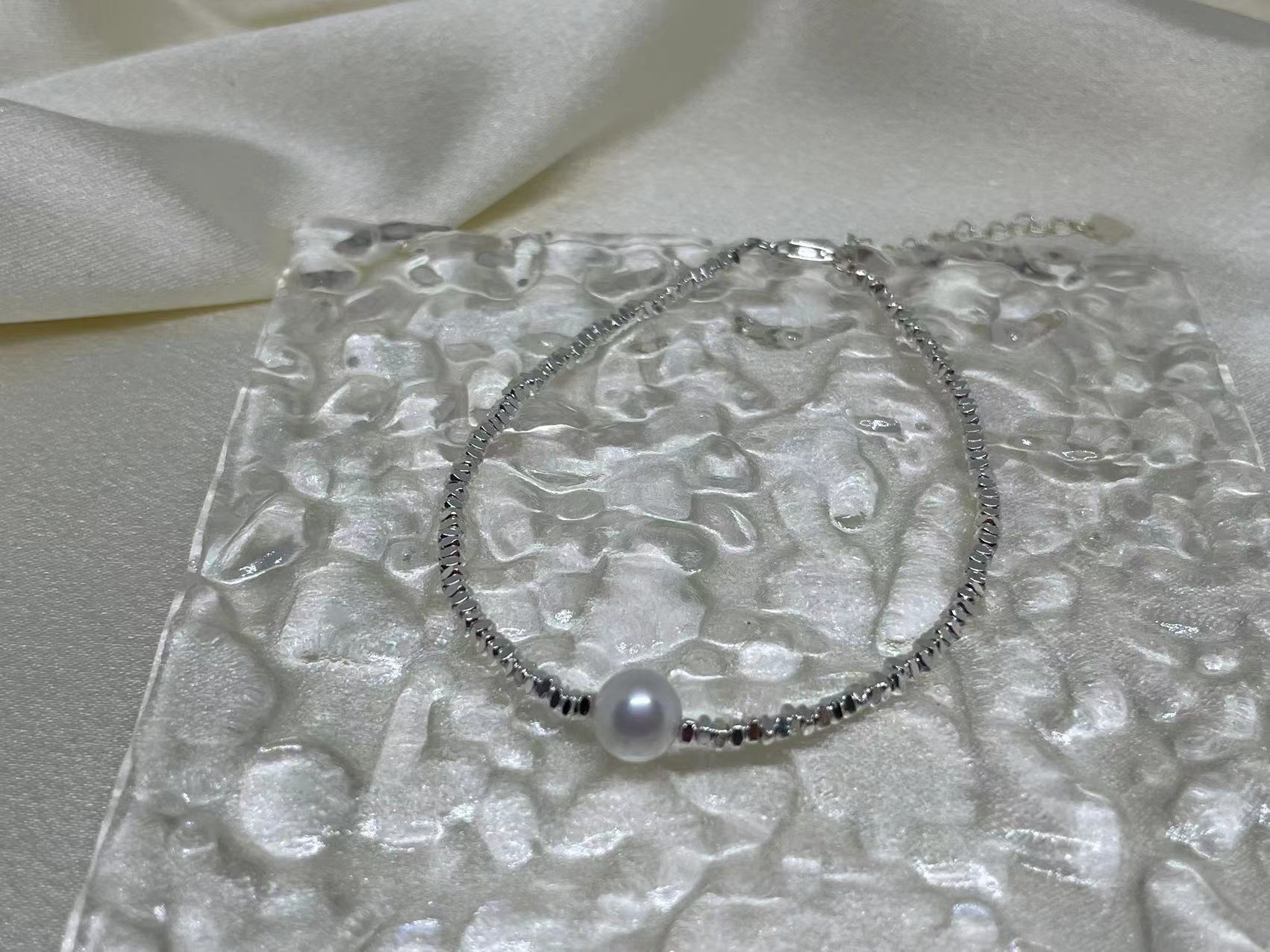 Freshwater pearl silver bracelet on a textured clear surface.