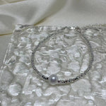 Freshwater pearl silver bracelet on a textured clear surface.