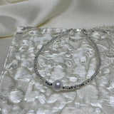 Freshwater pearl silver bracelet on a textured clear surface.