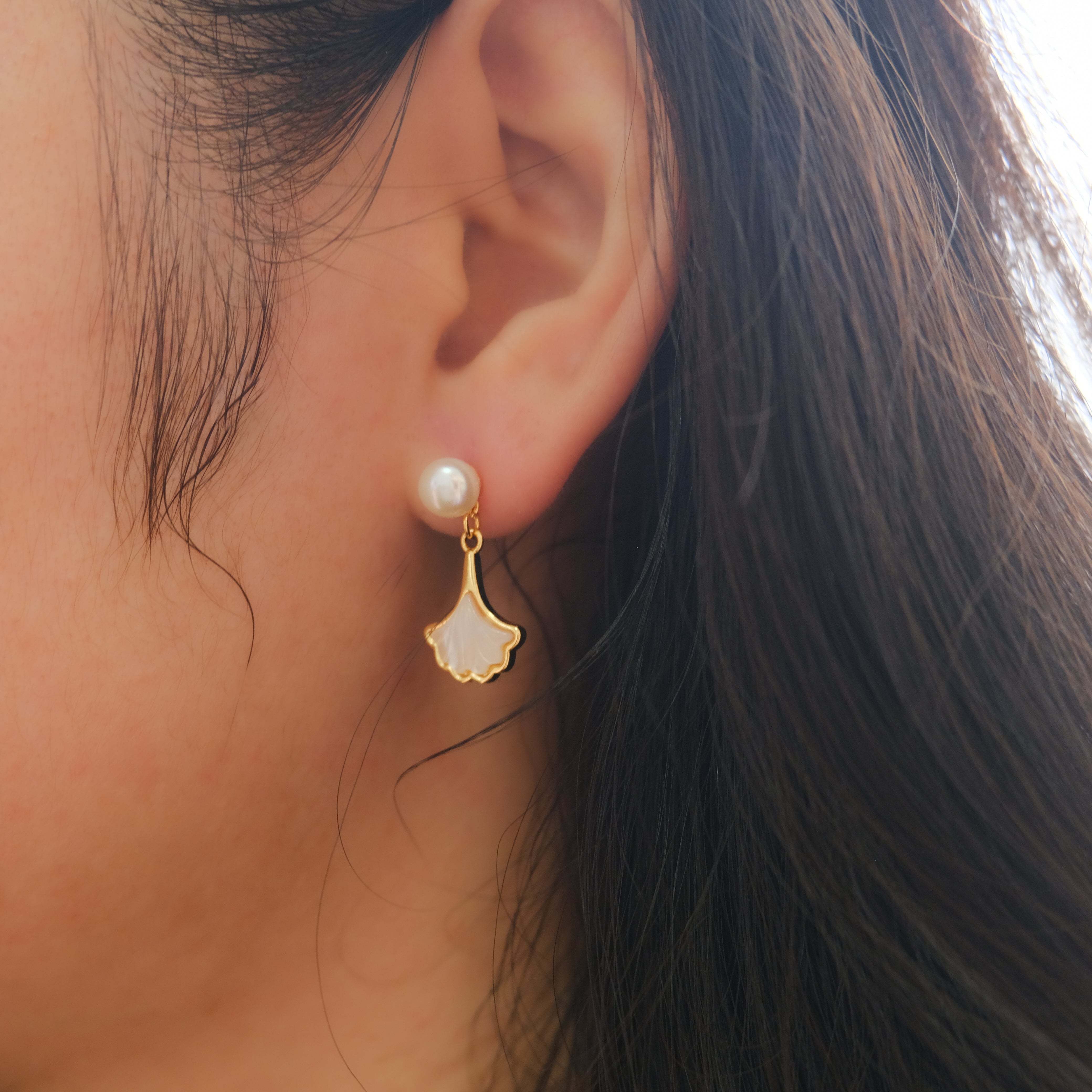 A woman wears a fan-shaped freshwater pearl dangle earring.