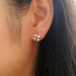 A close-up of a woman's ear wearing a four freshwater pearl rhomboid stud earring.