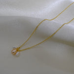 Gold chain necklace with three small, irregularly shaped pearls.