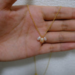 A gold chain necklace with three freshwater pearl pendants.