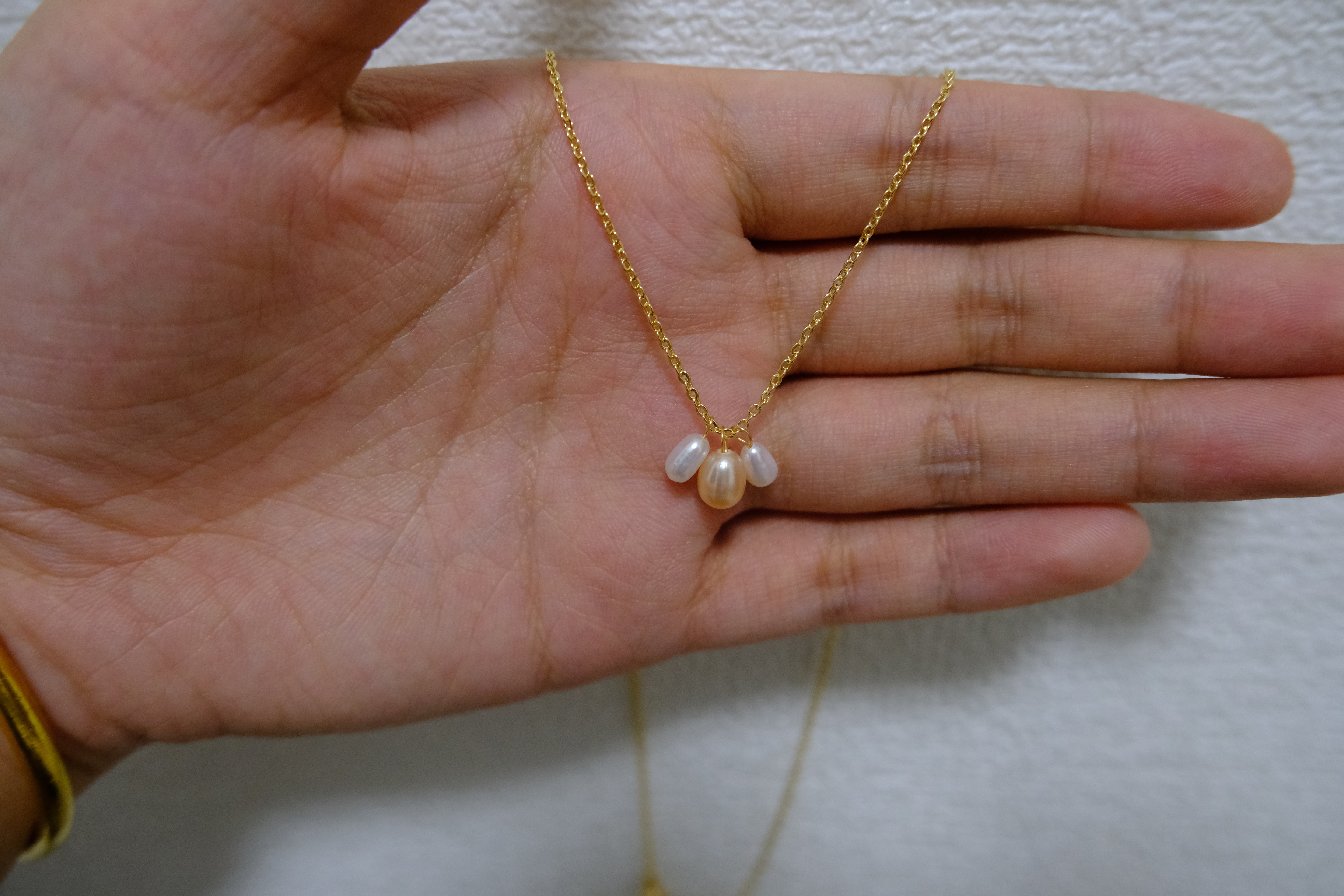 A gold chain necklace with three freshwater pearl pendants.