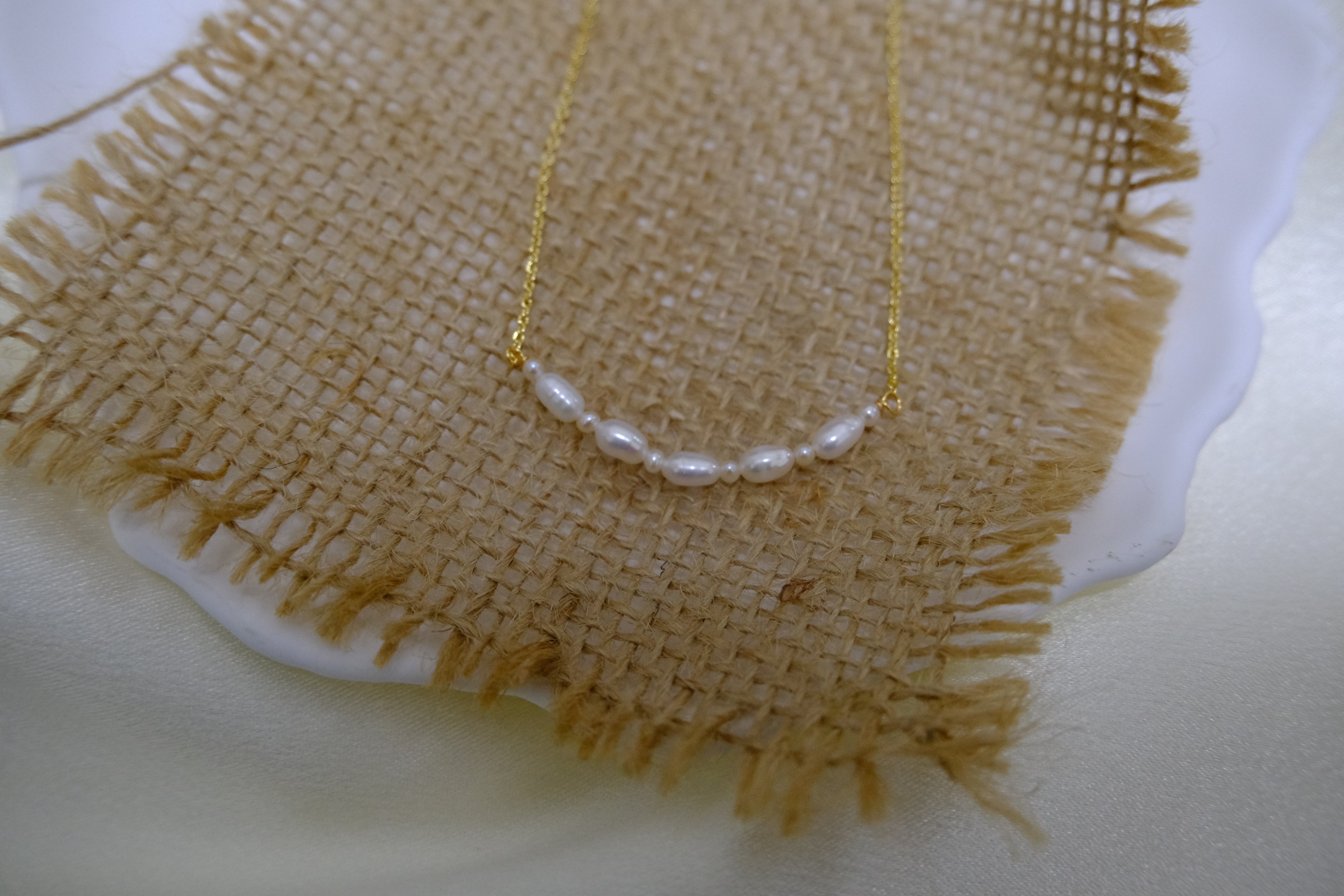 Real freshwater pearl bead necklace on a burlap surface.