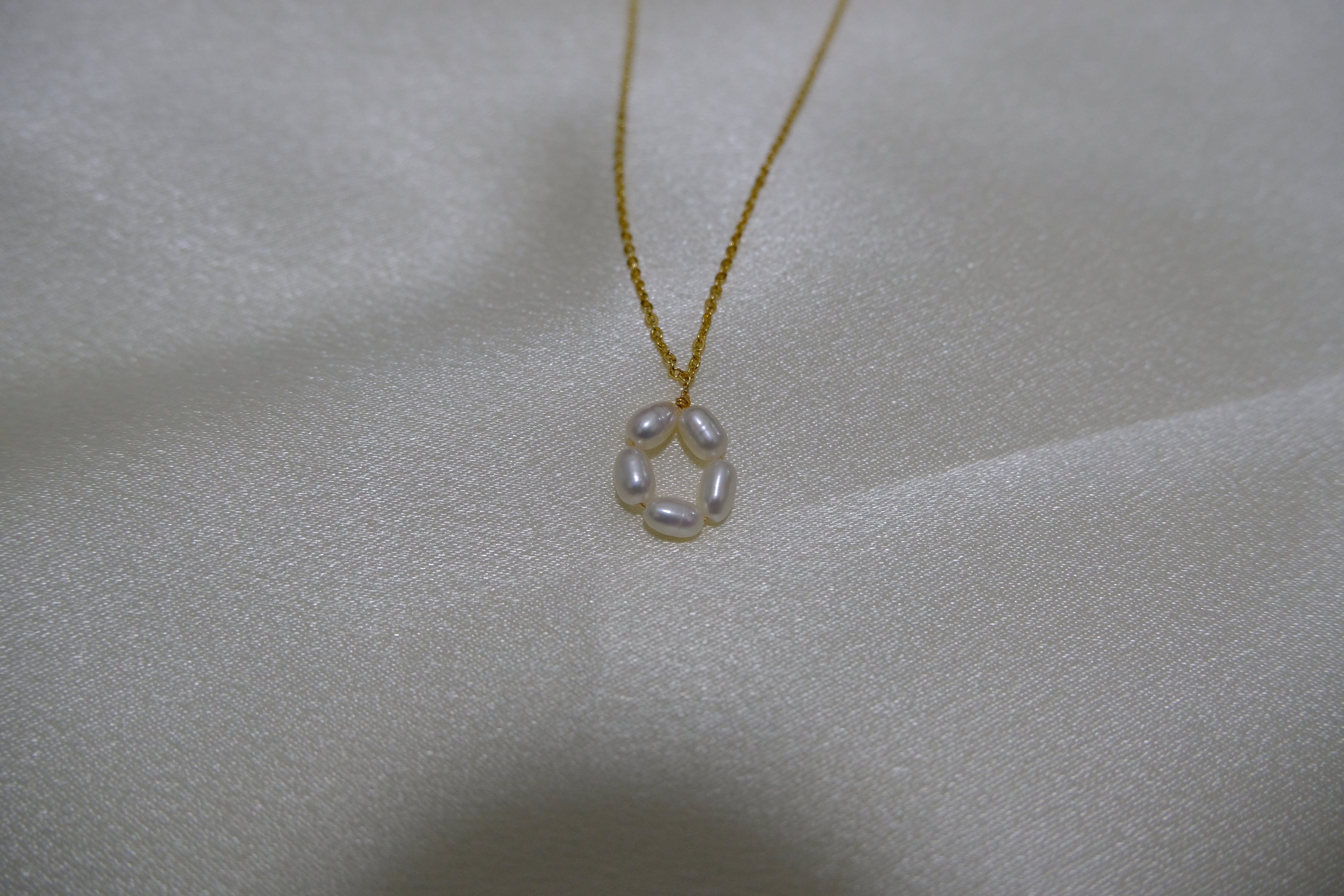 A gold-plated necklace with a pendant of five freshwater pearls arranged in a flower shape.