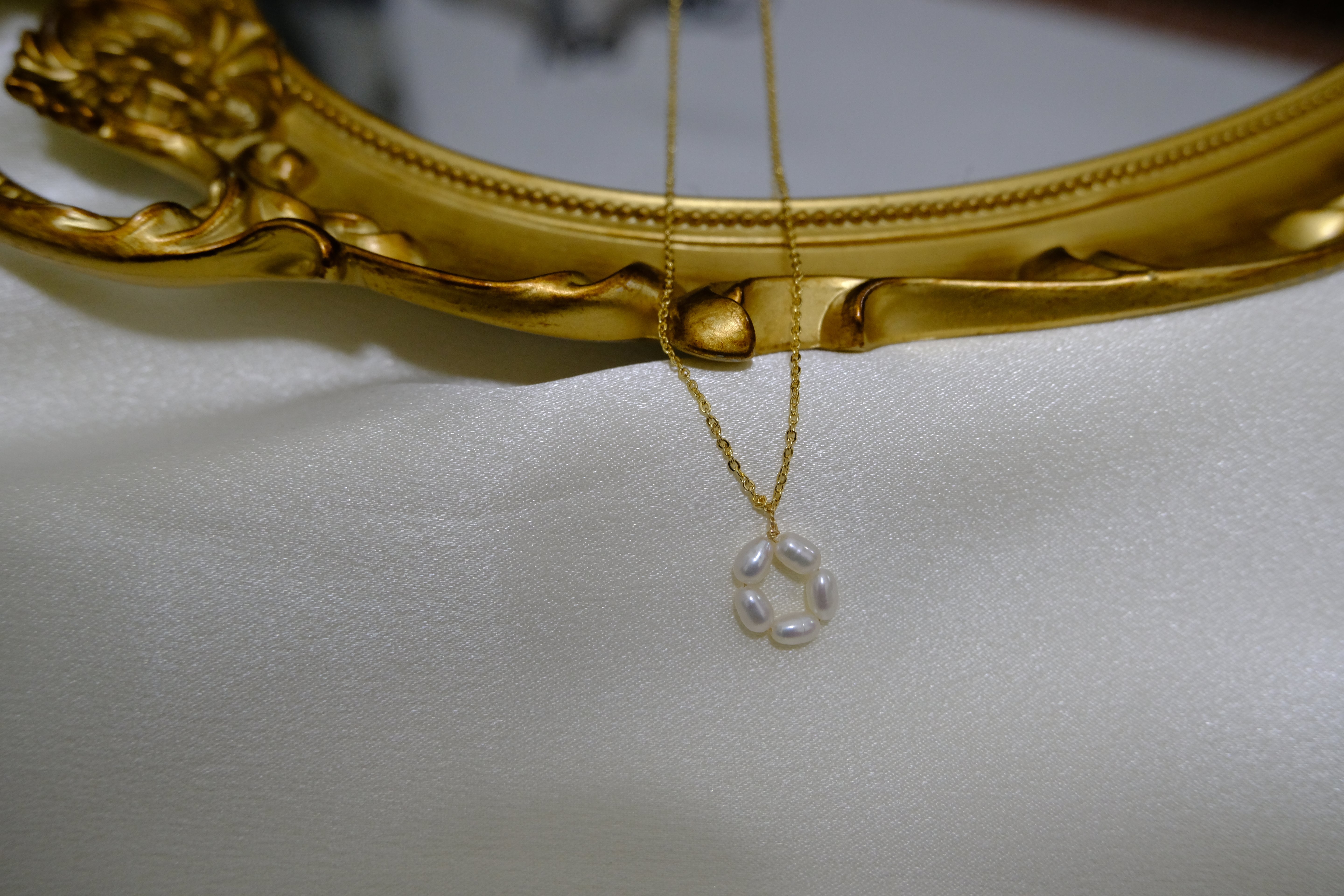 A gold-plated necklace with a pendant of five freshwater pearls arranged in a flower shape.