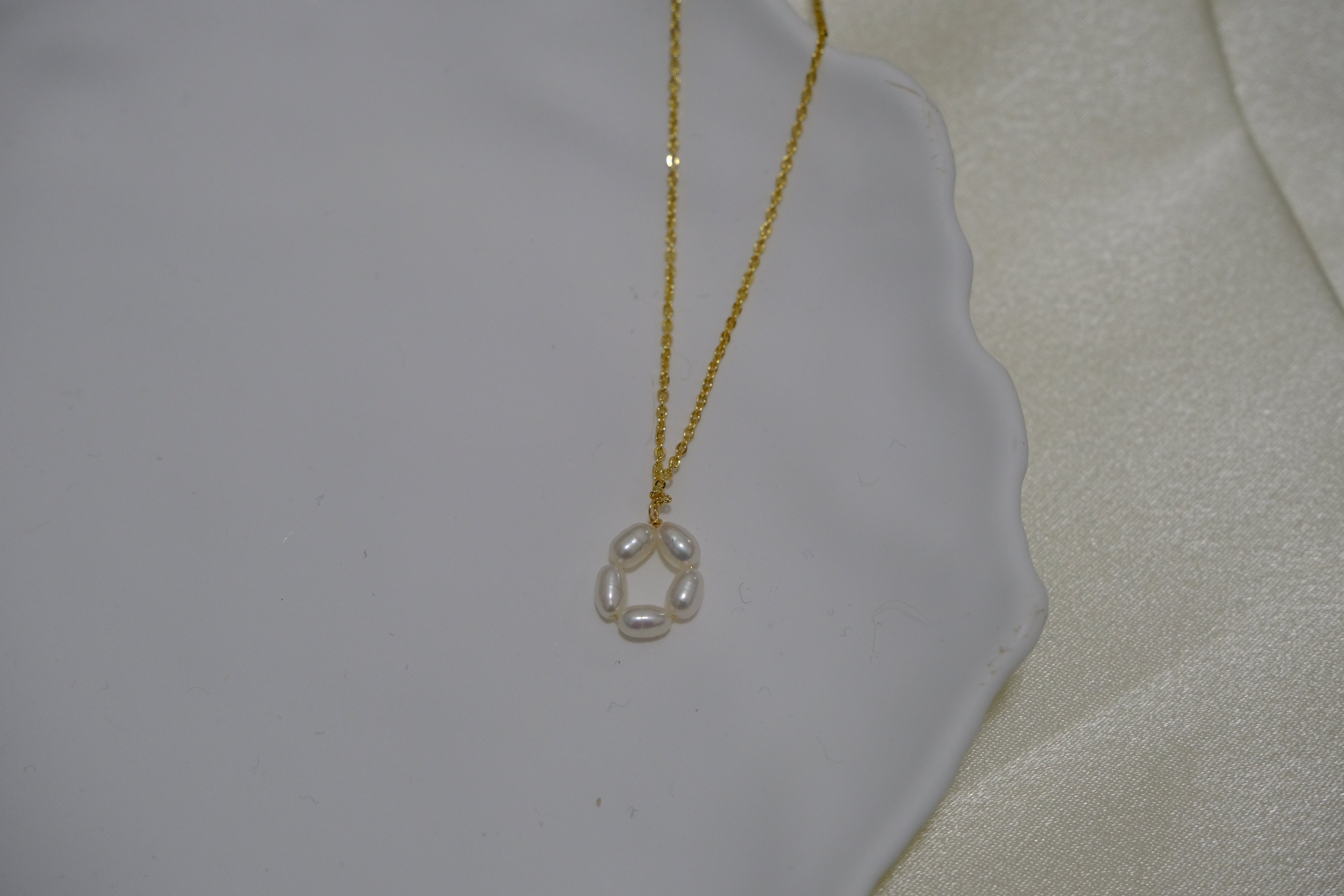 Gold-plated necklace with a pendant of five freshwater pearls arranged in a flower shape.
