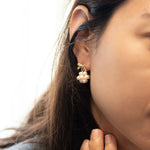 Gold-plated bowknot dangle freshwater pearl earring on a woman's ear.
