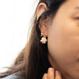 Gold-plated bowknot dangle freshwater pearl earring on a woman's ear.