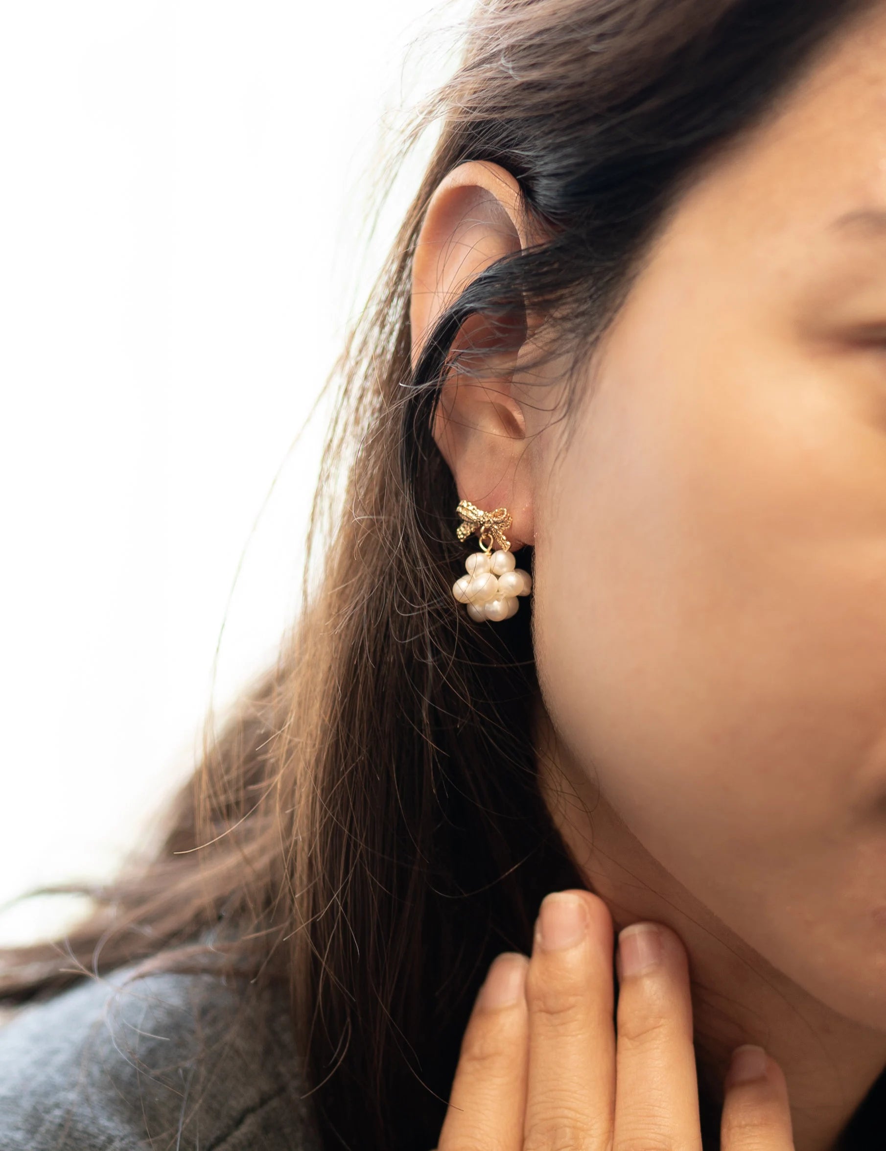 Gold-plated bowknot dangle freshwater pearl earring on a woman's ear.