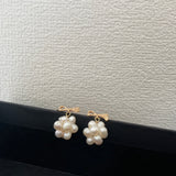 Gold-plated bowknot dangle freshwater pearl earrings are displayed on a black surface.