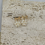 Gold-plated bowknot dangle freshwater pearl earrings on a textured stone surface.