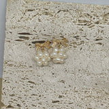 Gold-plated bowknot dangle freshwater pearl earrings on a textured stone surface.