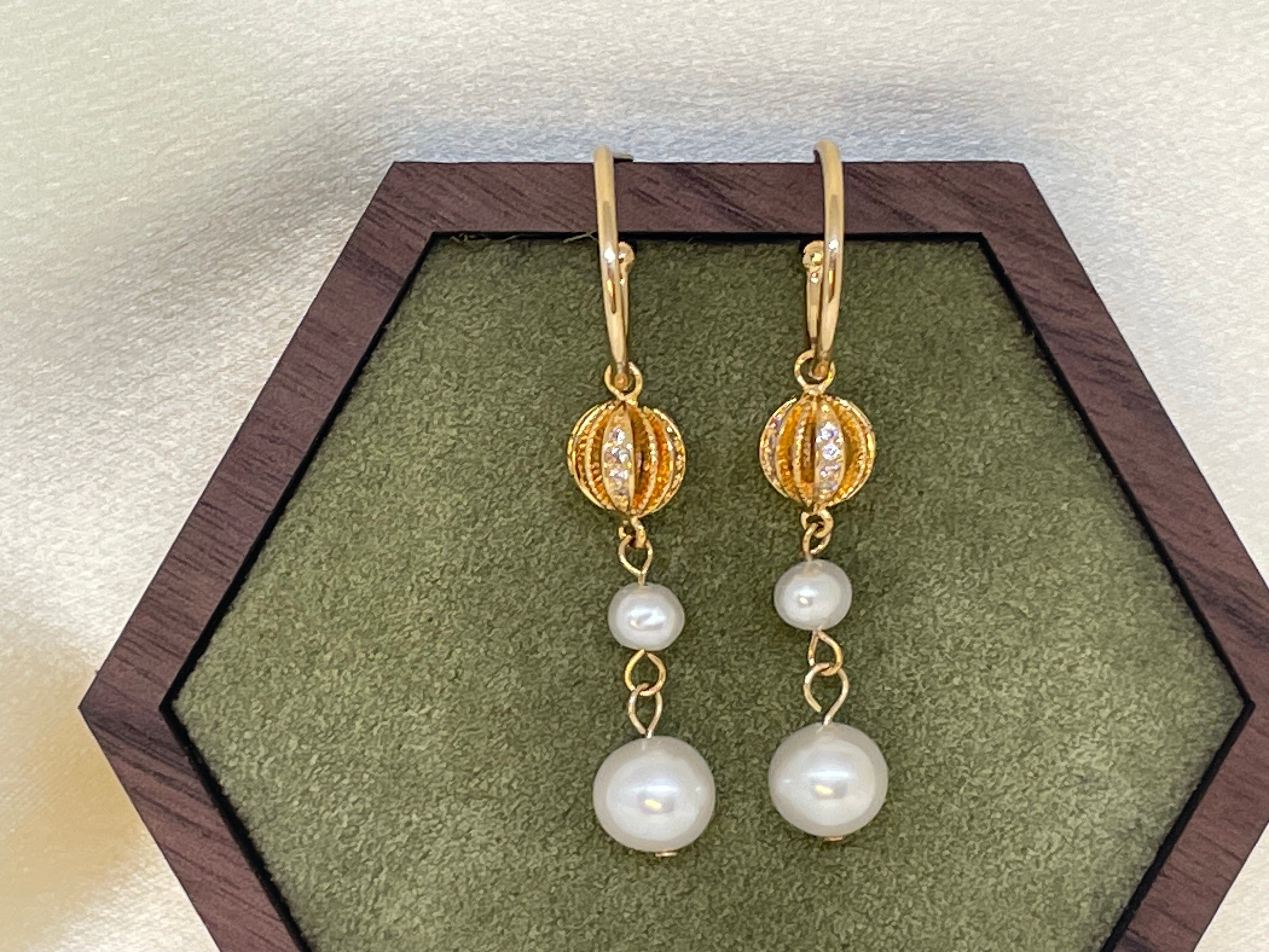 A pair of gold vintage-inspired drop earrings with two freshwater pearls each.