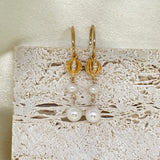 Two vintage freshwater pearl drop chain dangling earrings hang against a textured background.
