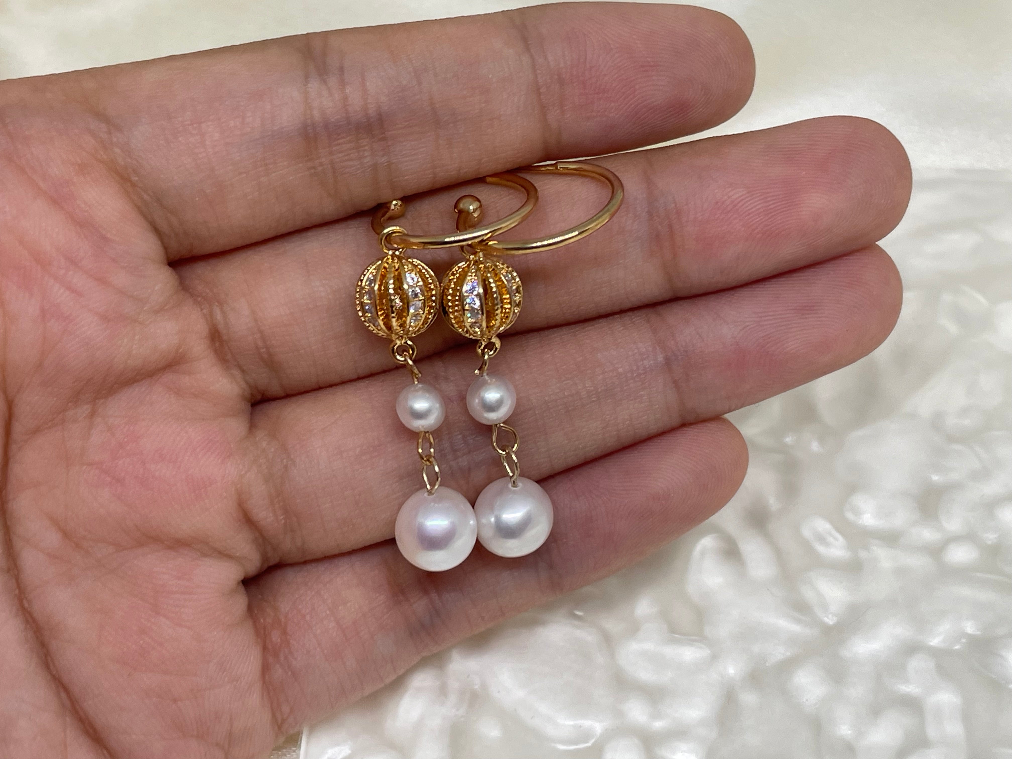 A pair of gold-toned drop earrings with two freshwater pearls each.