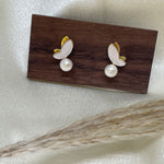 Gold-plated butterfly stud earrings with freshwater pearls on a wooden block.
