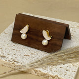 Gold-plated butterfly stud earrings with freshwater pearls on a wooden display.