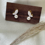 Gold-plated butterfly stud earrings with freshwater pearls on a wooden block.