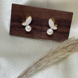 Gold-plated butterfly stud earrings with freshwater pearls on a wooden block.