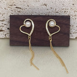 Two gold heart-shaped dangle earrings with a pearl in each heart.