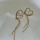 Gold heart-shaped dangle earrings with a single pearl and beaded chains.