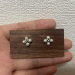 Four freshwater pearl rhomboid stud earrings on a wooden display.