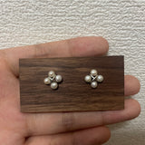 Four freshwater pearl rhomboid stud earrings on a wooden display.
