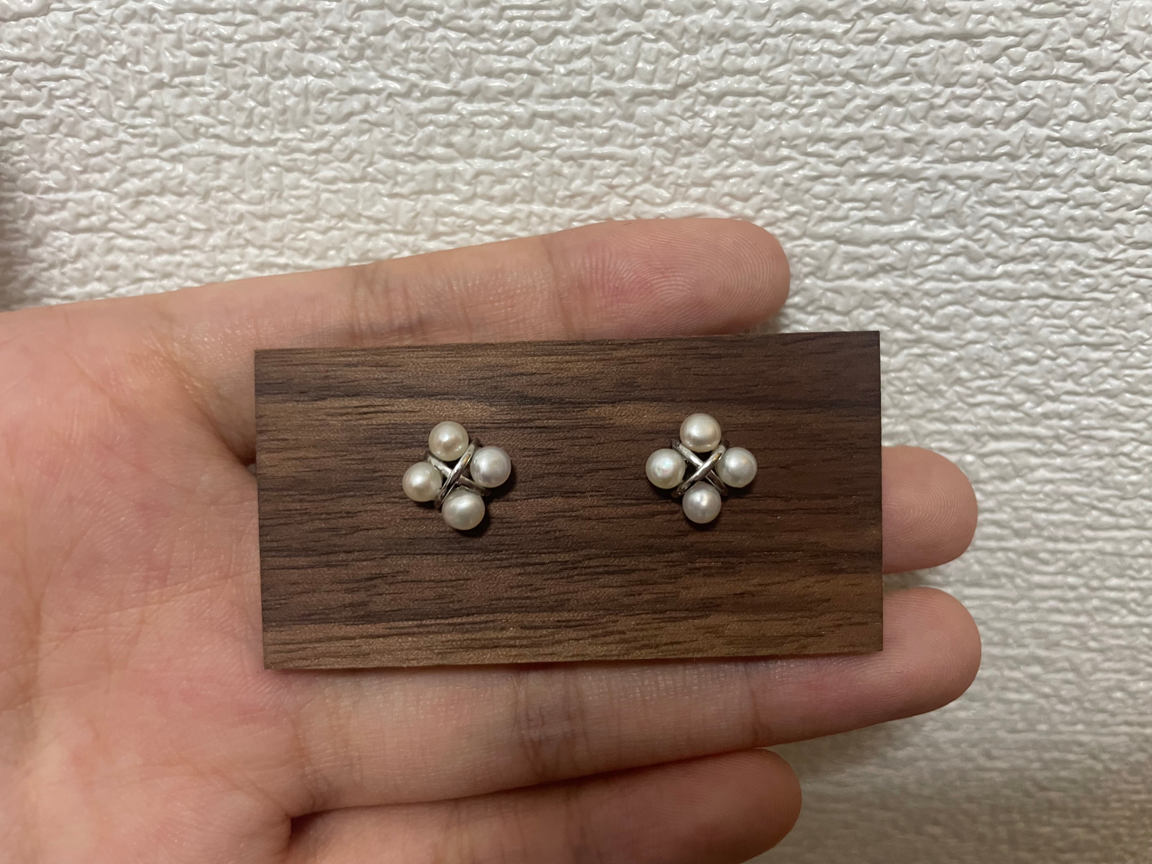 Four freshwater pearl rhomboid stud earrings on a wooden display.