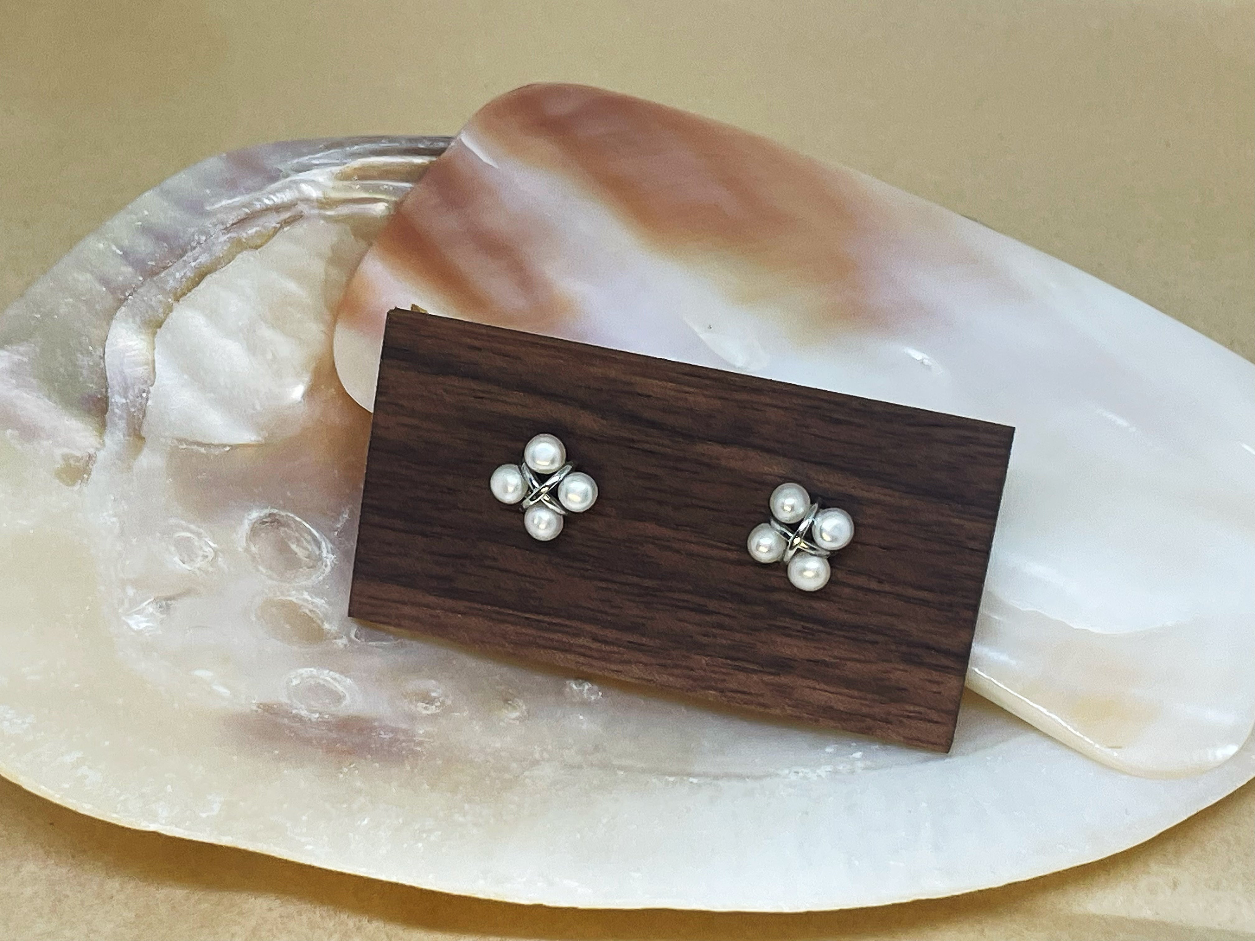 Four freshwater pearl rhomboid stud earrings on a wooden block.