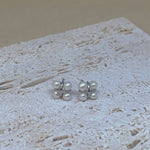 Four freshwater pearl rhomboid stud earrings on a textured surface.