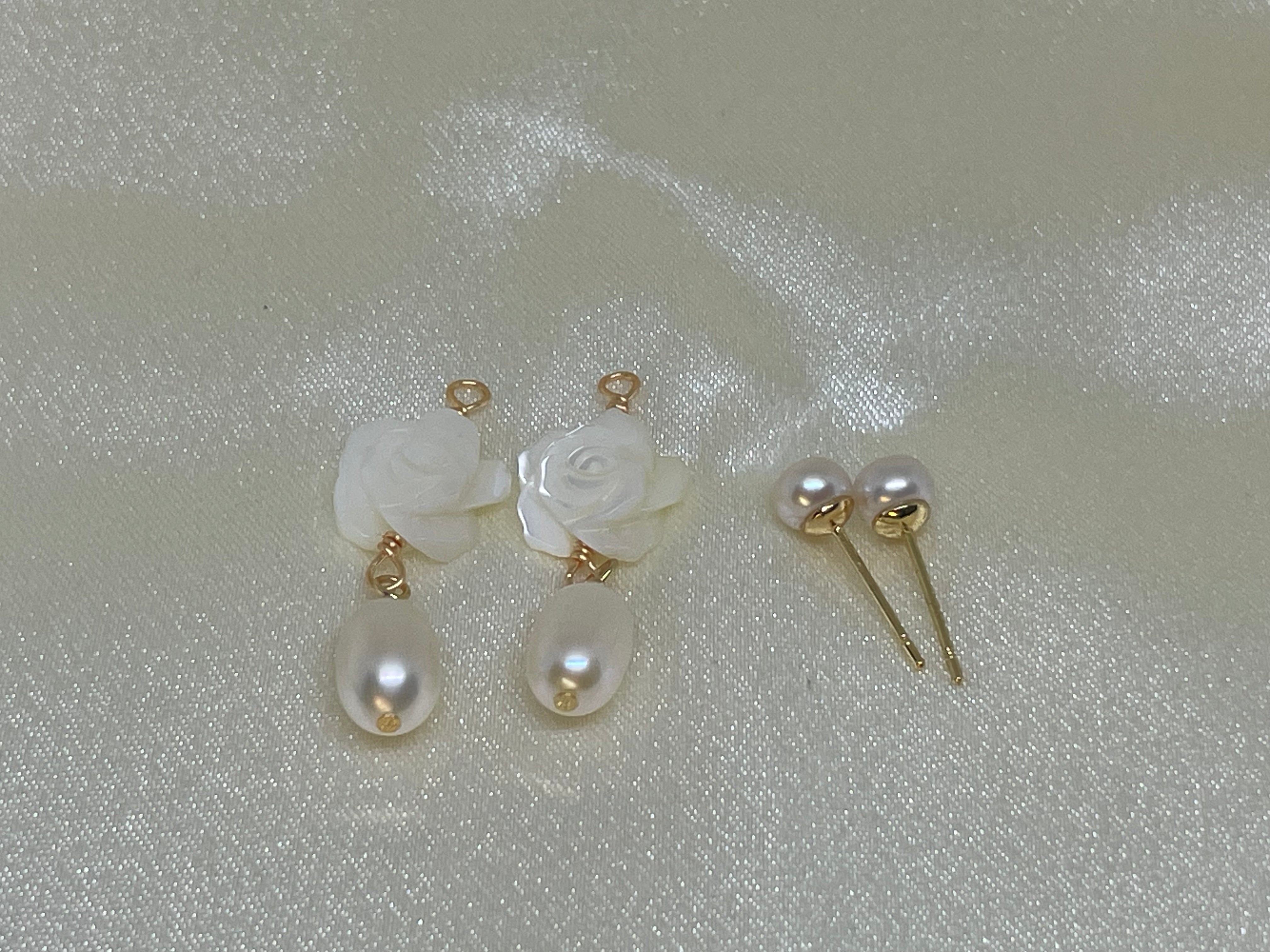 Elegant camellia freshwater pearl dangle earrings and pearl stud earrings on a shimmering surface.