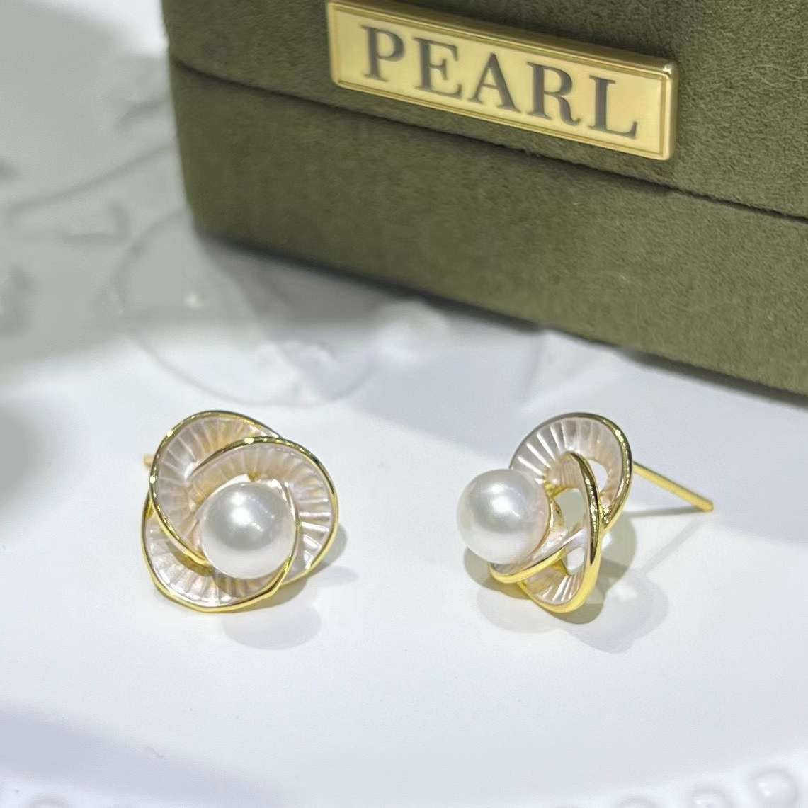 Trifoil freshwater pearl stud earrings with a gold setting and a green pearl box.