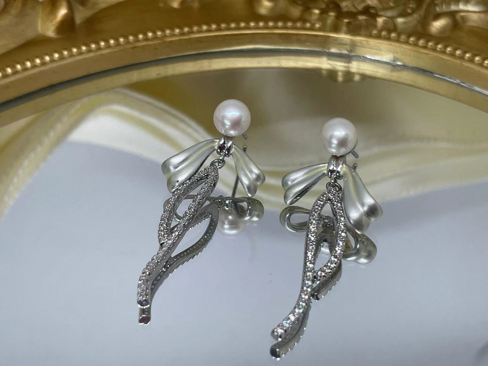 Elegant pearl bow dangle earrings with silver-plated chain and sparkling accents.