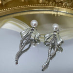 Elegant pearl bow dangle earrings with silver-plated chain and sparkling accents.