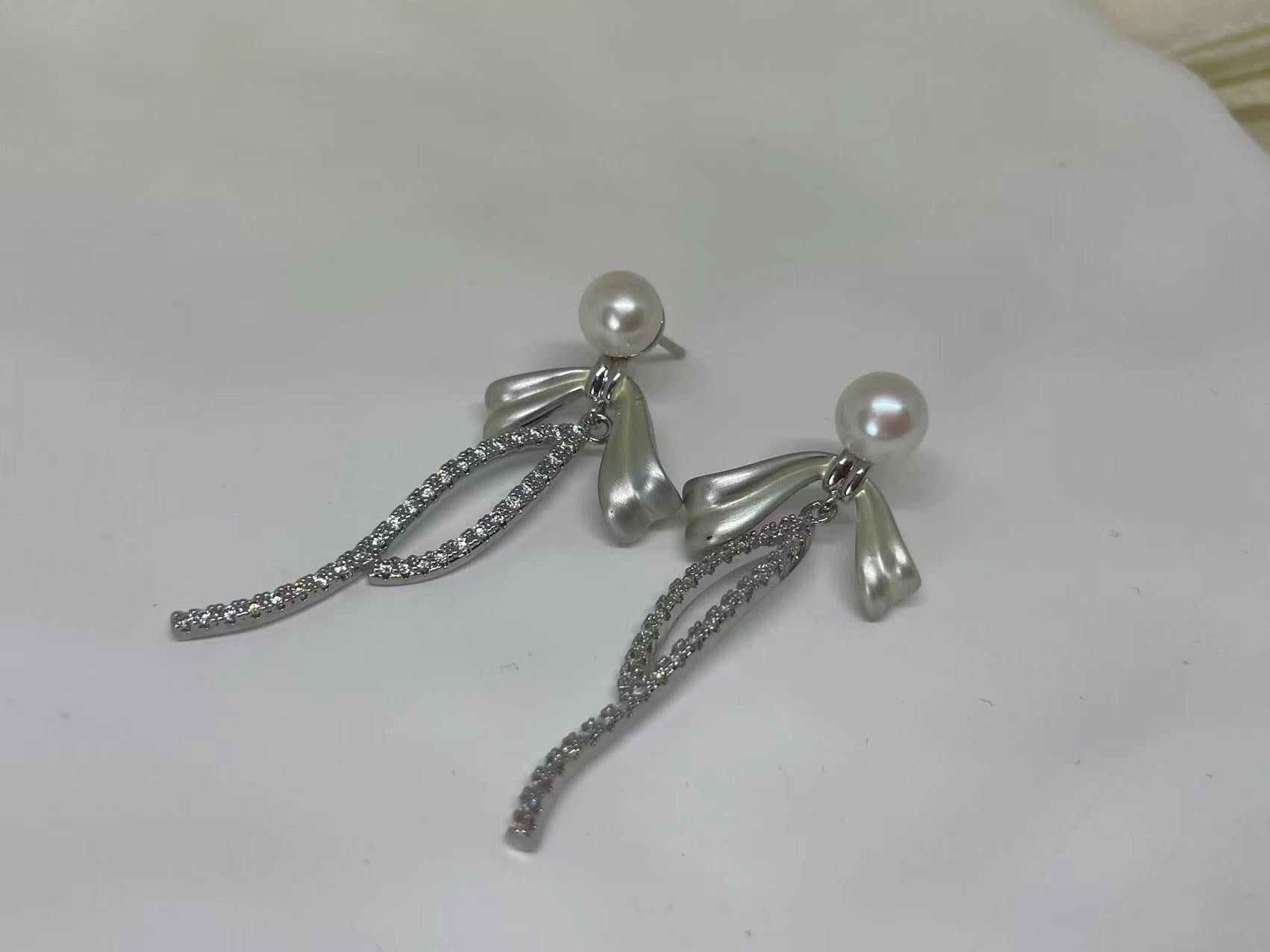 Elegant pearl bow dangle earrings with silver-plated chain and sparkling accents.