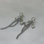 Elegant pearl bow dangle earrings with silver-plated chain and sparkling accents.
