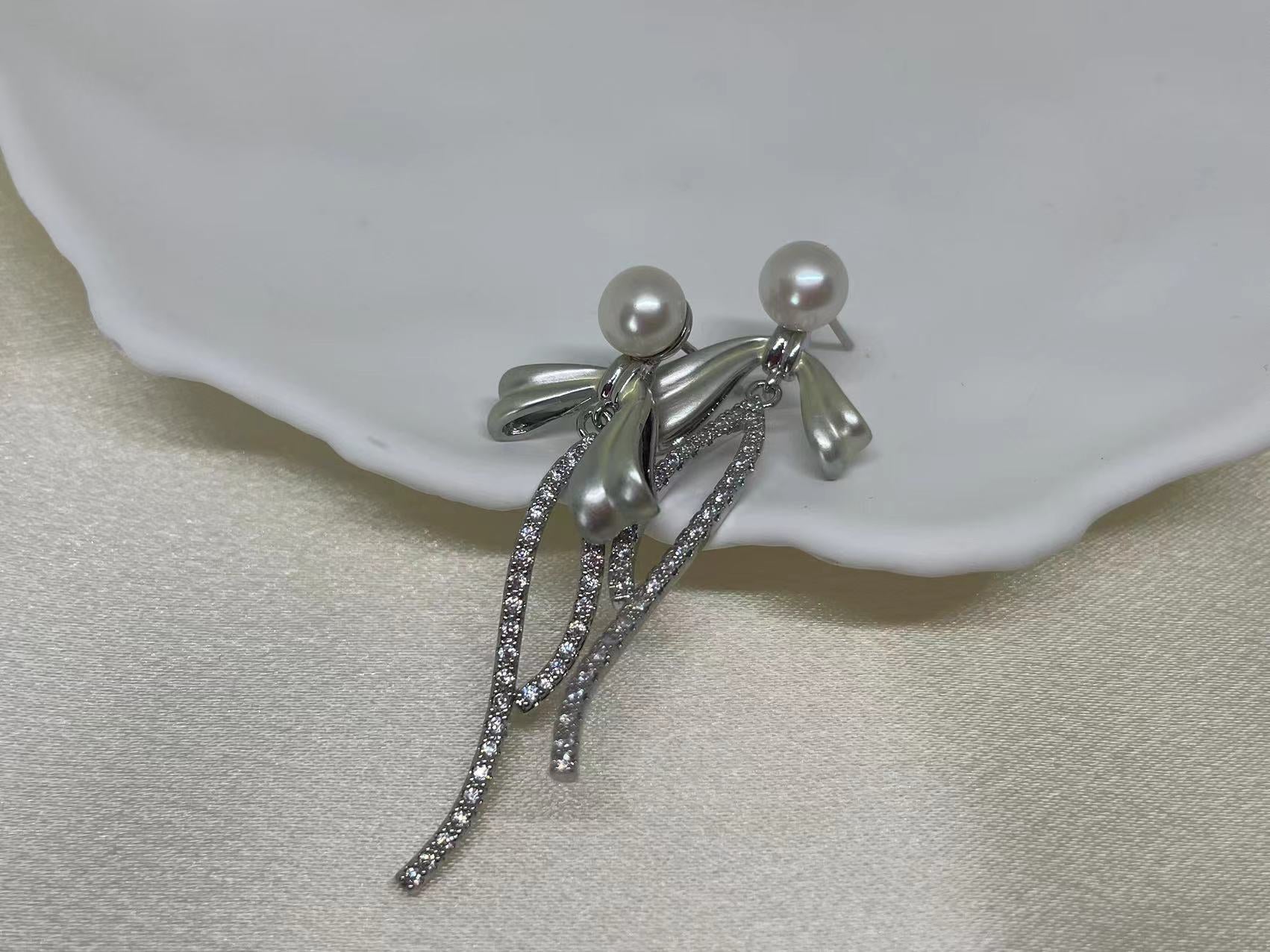 Elegant pearl bow dangle earrings with silver-plated chain and cubic zirconia.