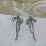 Elegant pearl bow dangle earrings with a silver-plated chain.