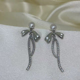 Elegant pearl bow dangle earrings with a silver-plated chain.