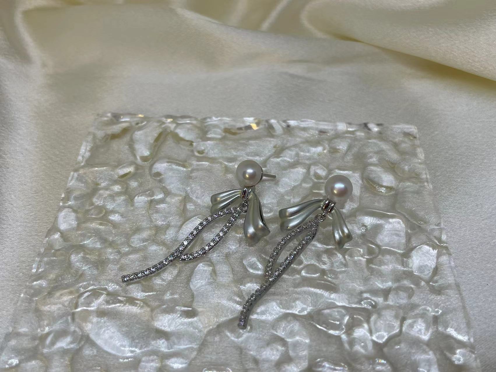 Elegant pearl bow dangle earrings with a silver-plated chain.