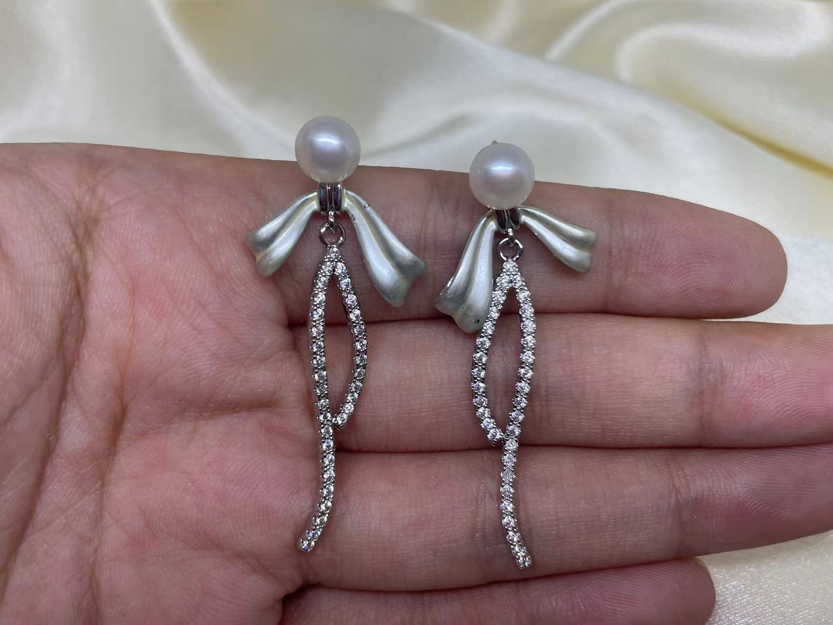 Elegant pearl bow dangle earrings with a silver-plated chain and cubic zirconia.