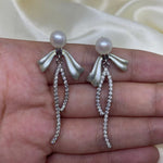 Elegant pearl bow dangle earrings with a silver-plated chain and cubic zirconia.