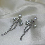 Elegant pearl bow dangle earrings with a silver-plated chain and cubic zirconia accents.