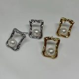Four stud earrings, two gold and two silver, feature a pearl in a quadrate frame.