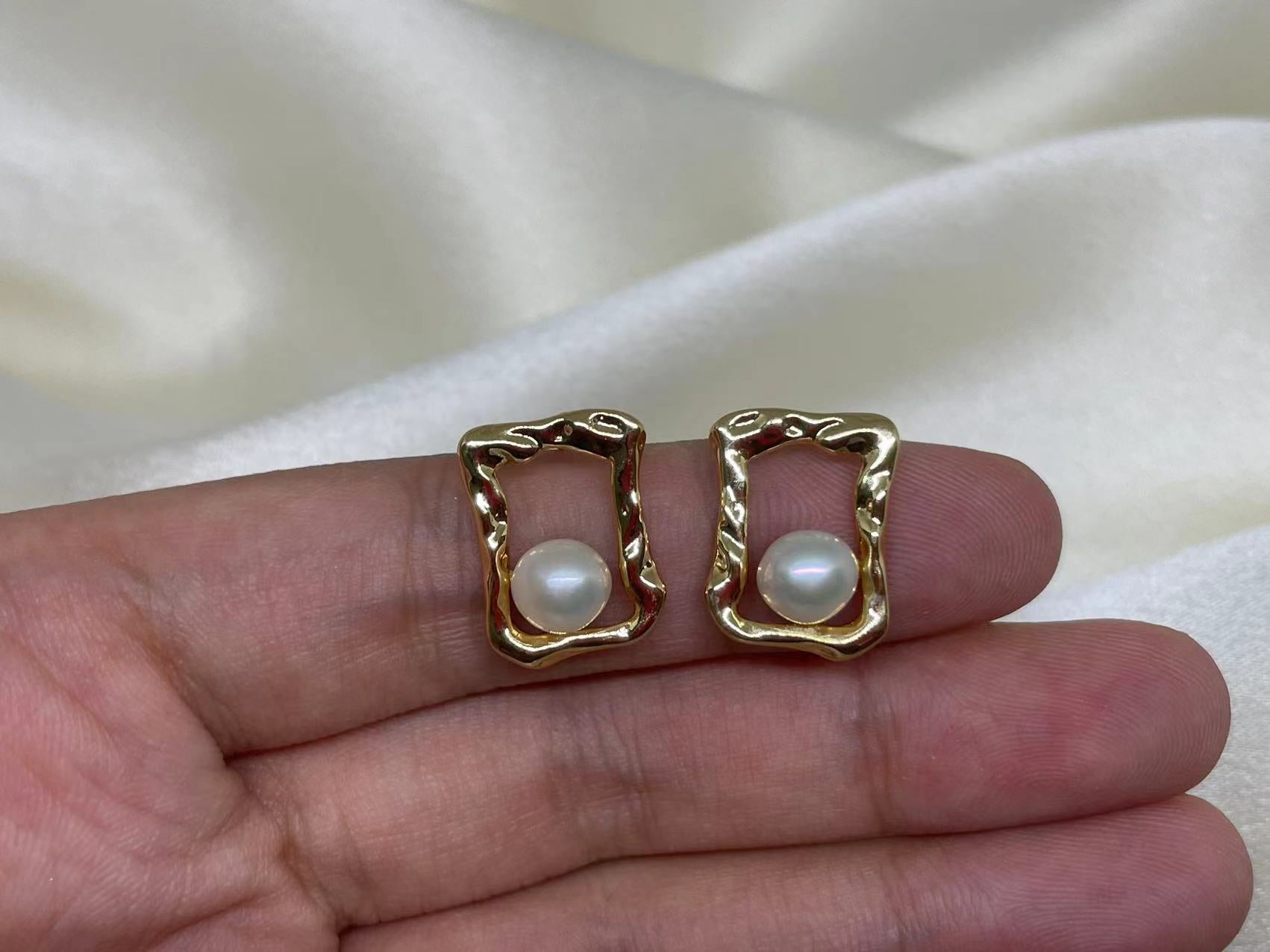 Gold quadrate stud earrings with a single freshwater pearl in each.